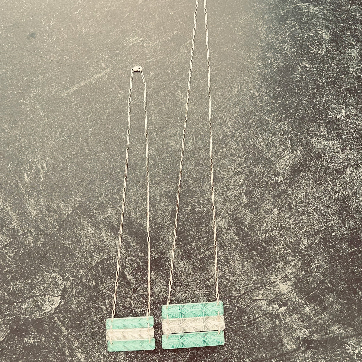 Sea Turtle Pattern 3 bar necklace in alternating green and white.  shown on dark surface to emphasize different chain lengths.