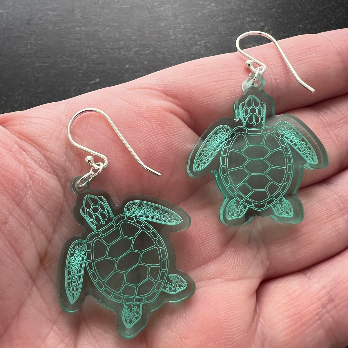 Sea turtle earnings shaped earrings, Large size, shown in hand to show size-lightweight green acrylic, laser cut with sterling silver ear wires.