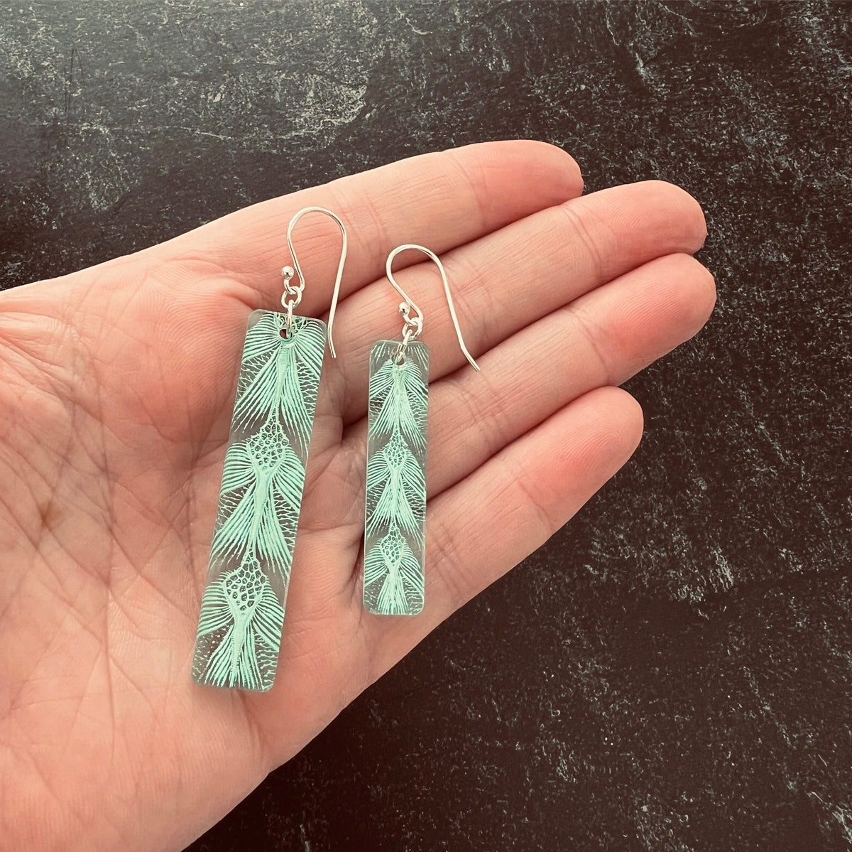 Turtle Patterned earring in long bar - showing size difference in hand green.