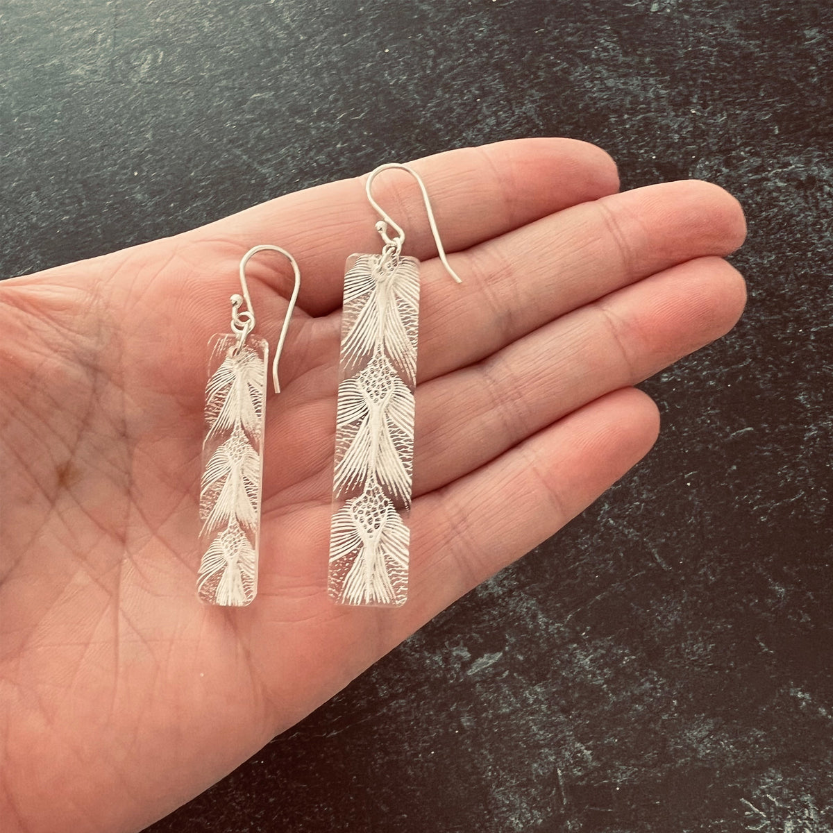 Turtle Patterned earring in long bar - showing size difference in hand white.