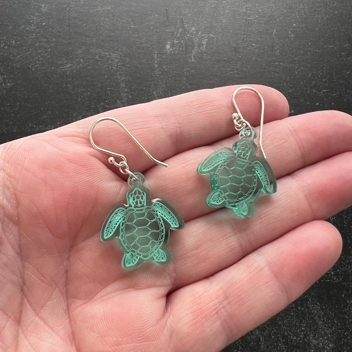 Sea turtle earnings shaped earrings, small size shown in hand to indicate scale, lightweight green acrylic, laser cut with sterling silver ear wires.
