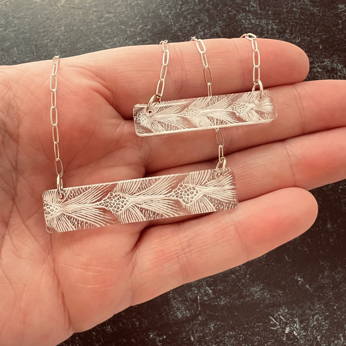 Size comparison of small and large bar Necklaces with sea turtle pattern in white in hand.